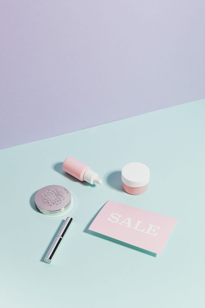 about-us Minimalist flat lay of beauty products and sale sign on pastel background.