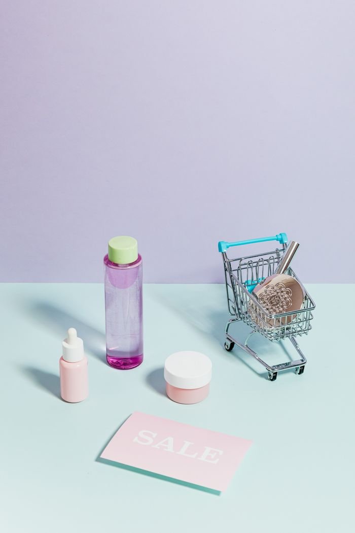 our-story Elegant flatlay of cosmetics and a mini shopping cart, ideal for sales promotions.