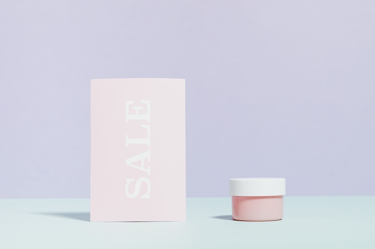 about-us Elegant still life of a sale card and cream jar on pastel background.