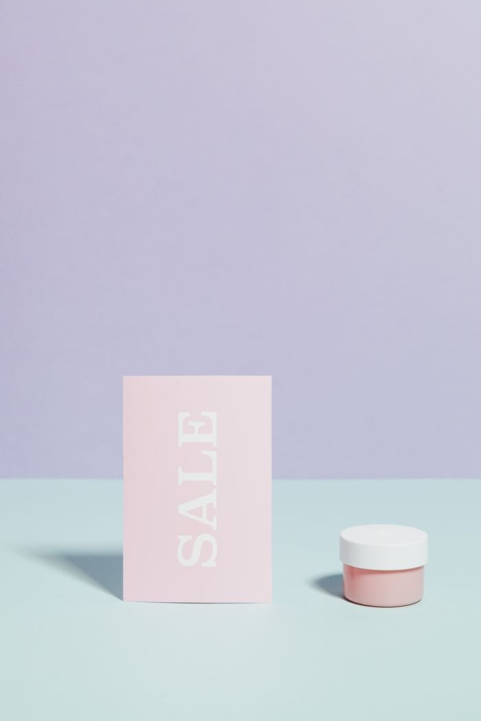 Pastel themed flat lay showcasing a beauty product beside a sale sign, ideal for promotions.