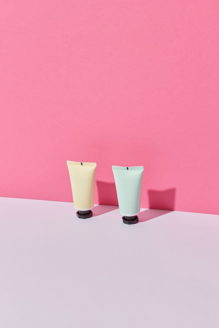 services-01 Two pastel-colored tubes on a pink background, perfect for beauty product promotions.